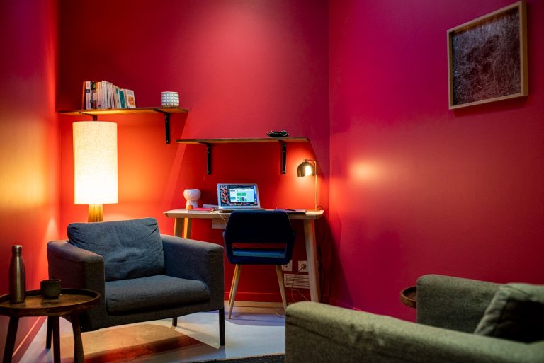 Le cabinet Rose : murs framboise, deux fauteuils et un petit bureau éclairé