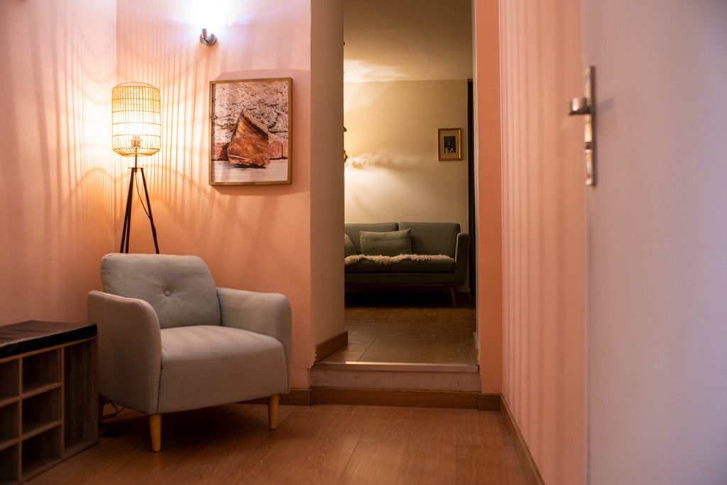 L'entrée de L'Arbre Bleu : un fauteuil sous une lampe, et le salon d'attente au fond