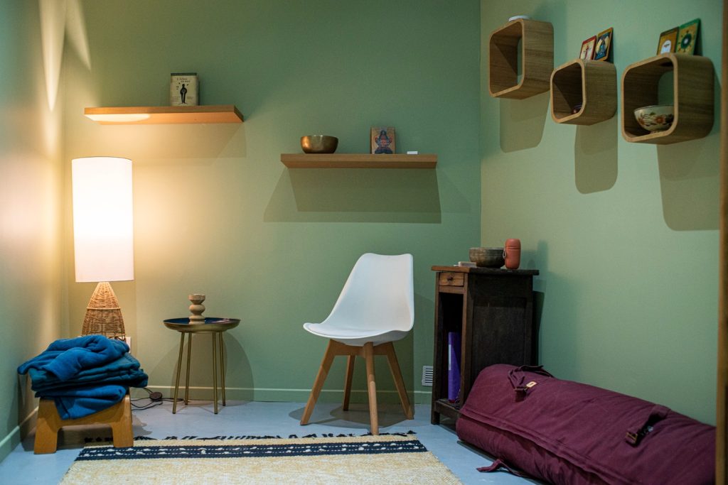 La cabine de soins de L'Arbre Bleu : murs vert tendre, lumière douce, couvertures et futon